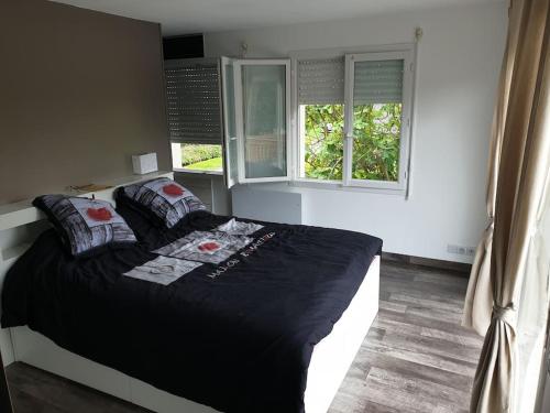 - un lit dans une chambre avec 2 fenêtres dans l'établissement Côté Mer - Jardin privatif à 200m de la plage, à Ver-sur-Mer