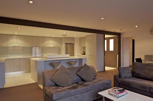 a living room with a couch and a kitchen at Zero Davey Boutique Apartment Hotel in Hobart