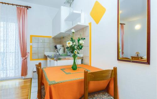 una mesa de comedor con un jarrón de flores. en Lovely Apartment In Omis With Kitchenette, en Omiš