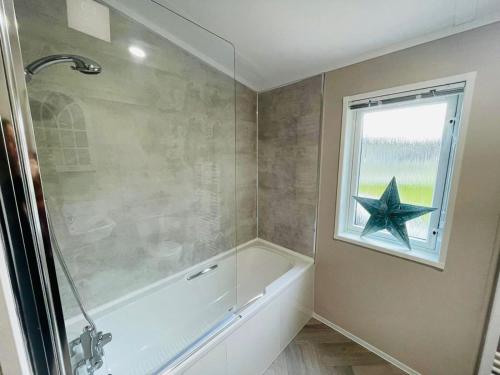 a bathroom with a bath tub and a star on the window at Happy Days Lodge with Hot Tub in York