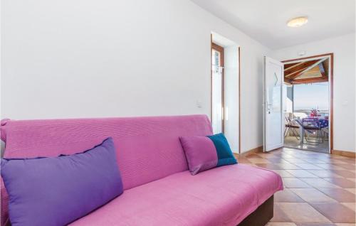 a pink couch in a living room with a view of the ocean at 2 Bedroom Nice Apartment In Veli Jezenj in Veli Ježenj