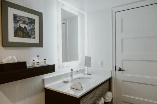 a white bathroom with a sink and a mirror at Crowne Plaza Fredericton Lord Beaverbrook by IHG in Fredericton