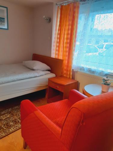 a bedroom with a bed and a chair and a window at Pokoje Gościnne in Gdańsk