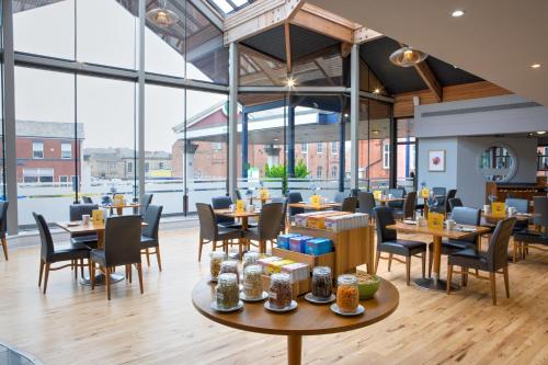 a restaurant with tables and chairs and large windows at Holiday Inn Bolton Centre by IHG in Bolton