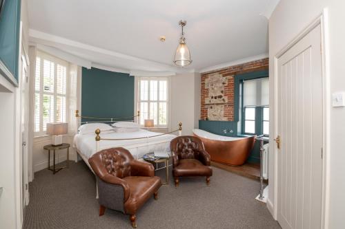 a bedroom with a bed and two chairs and a tub at The Lodge in Hunstanton