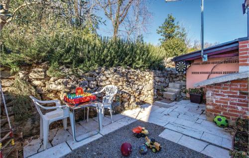 a small backyard with a table and chairs and a stone wall at 1 Bedroom Awesome Apartment In Volosko in Volosko