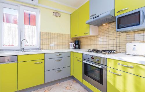 a kitchen with yellow cabinets and a stove top oven at 1 Bedroom Awesome Apartment In Volosko in Volosko