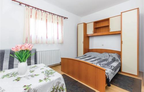 a bedroom with a bed and a table with a vase of flowers at 1 Bedroom Cozy Apartment In Kostrena in Kostrena