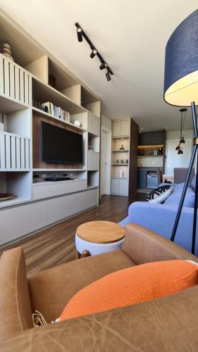 a living room with a couch and a tv at Conforto e sofisticação à 500m da Vila Germânica in Blumenau
