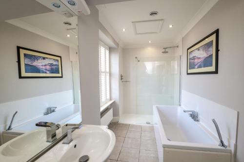 a white bathroom with a sink and a tub and a sinkonnaissance at The Lodge in Hunstanton