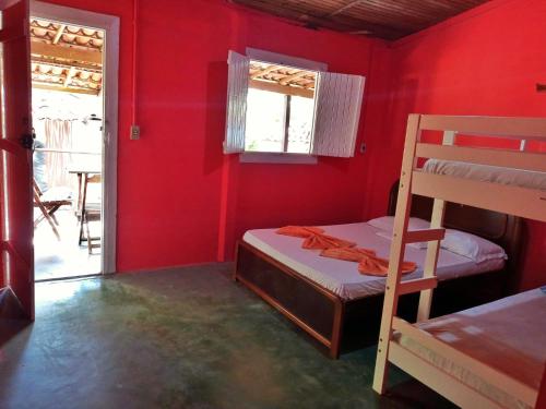 a room with two bunk beds and a red wall at Aldeia das Flores - Hostel e Camping in Jacumã
