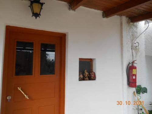 a red door on a white building with a fire extinguisher at Melios Rooms in Petalidhion