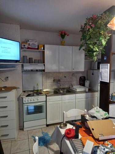 a kitchen with white cabinets and a stove and a table at Apartments Lidija in Pag