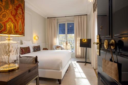 une chambre avec un grand lit blanc et un canapé dans l'établissement Hôtel de Banville, à Paris