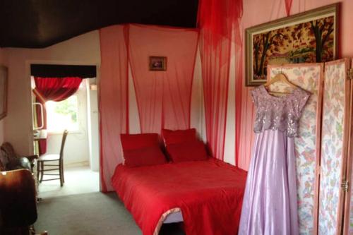 um quarto com uma cama vermelha com um vestido em Maison de 6 chambres avec jardin et wifi a La Caillere Saint Hilaire em Mérigny