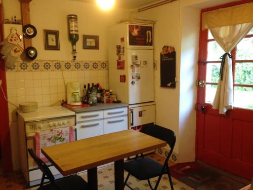 La cuisine est équipée d'une table, d'un réfrigérateur et d'une cuisinière. dans l'établissement Maison de 6 chambres avec jardin et wifi a La Caillere Saint Hilaire, à Mérigny
