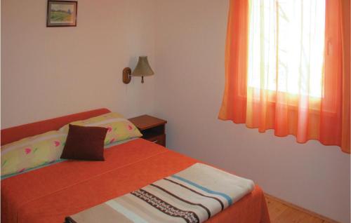 a bedroom with a bed with an orange blanket and a window at 2 Bedroom Cozy Home In Bosiljevo in Bosiljevo