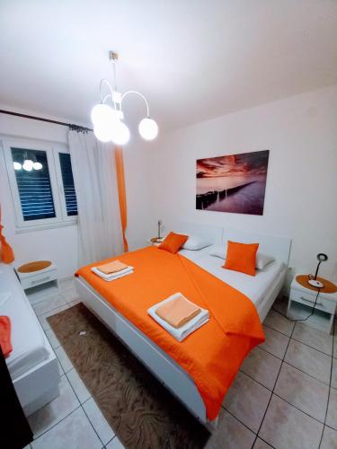 a bedroom with a large bed with an orange blanket at Apartments Lidija in Pag