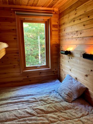 a bedroom with a window in a log cabin at Bergen/Sotra: Sea cabin. Spa. Fishing. Boat in Haganes