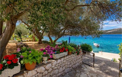 a retaining wall with flowers and a body of water at 2 Bedroom Awesome Apartment In Stara Novalja in Stara Novalja