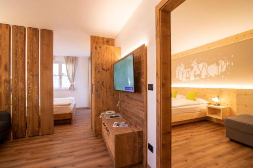 a room with a bed and a tv on a wall at Residence Montebel in Tesero