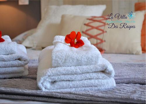 einen Stapel Handtücher mit einer roten Blume auf dem Bett in der Unterkunft La Villa Des Raspes - Holistique Spa - Adult Only in Viala-du-Tarn