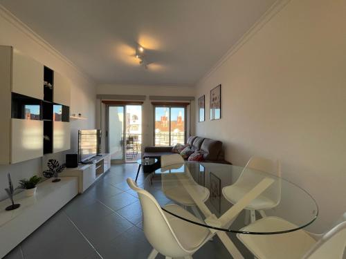 a living room with a glass table and white chairs at T1 ocean view close to Praia da Oura in Albufeira