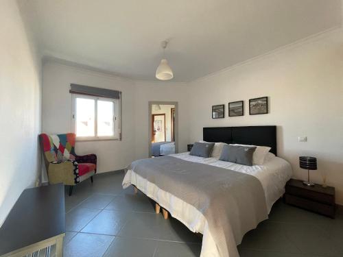 a bedroom with a large bed and a chair at T1 ocean view close to Praia da Oura in Albufeira