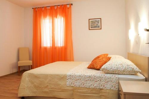 a bedroom with a bed with an orange curtain at Apartment Anna Maria in Promajna
