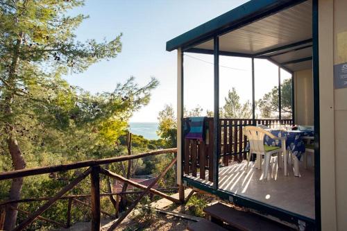 a house with a deck with a table and a view of the ocean at Camping Europa in Capoliveri