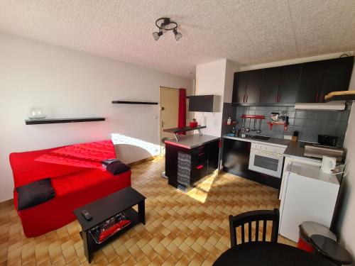 a bedroom with a red bed and a kitchen at Apartment Viktor II in Vinon-sur-Verdon