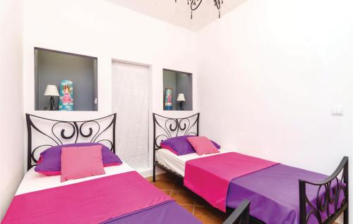 two beds in a bedroom with pink and purple sheets at 2 Bedroom Awesome Apartment In Ratac in Orasac