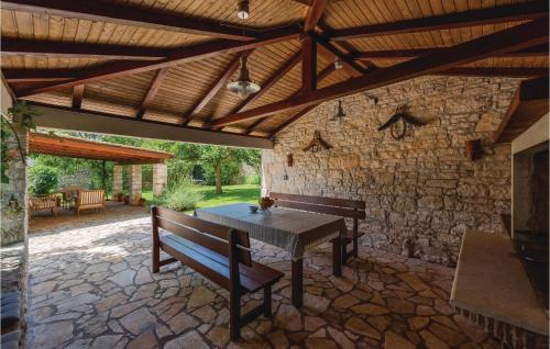 a patio with a table and benches and a stone wall at Holiday Home Butkovici Croatia in Butkovići