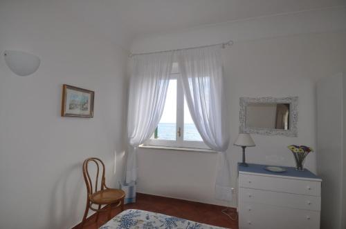 a bedroom with a window and a dresser and a chair at La Zinefra Amalfi Dreams in Minori