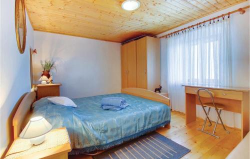 a bedroom with a blue bed and a desk and a desk at Lovely Apartment In Valun With Kitchen in Valun