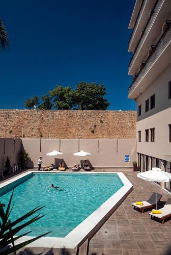 a swimming pool with a person in the water next to a building at Kriti Hotel in Chania Town