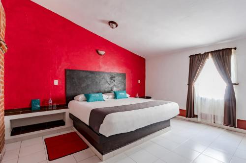 a bedroom with a large bed with a red wall at Ayenda Mesón del Río in Tepotzotlán