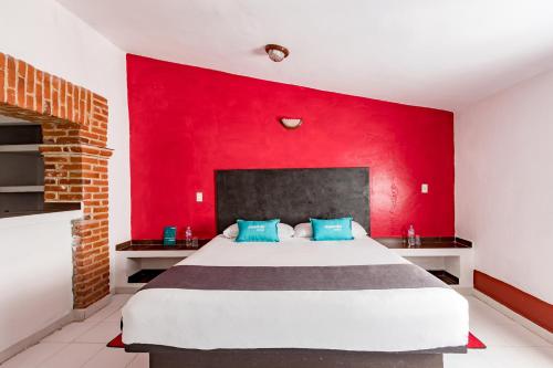 a bedroom with a large bed with a red wall at Ayenda Mesón del Río in Tepotzotlán