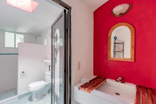 a bathroom with a red wall and a toilet at Ayenda Mesón del Río in Tepotzotlán