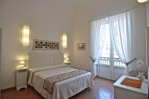 a white bedroom with a bed and a balcony at Braschi Amalfi Dreams in Minori