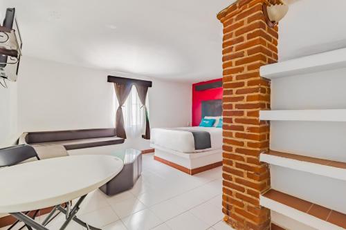 a bedroom with a bed and a table and a brick wall at Ayenda Mesón del Río in Tepotzotlán
