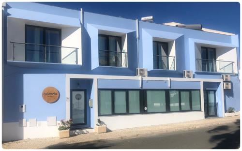 a blue building with a sign on it at Calmaria Guesthouse in Porto Covo