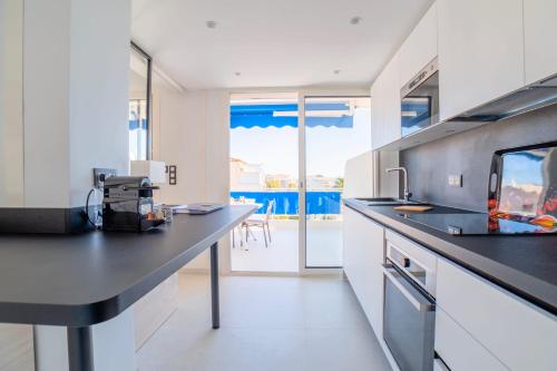 une cuisine avec comptoirs blancs et comptoir noir dans l'établissement 1-Br Apartment Sea View Terrace & Parking, à Cannes