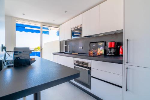 une cuisine avec des armoires blanches et un comptoir noir dans l'établissement 1-Br Apartment Sea View Terrace & Parking, à Cannes