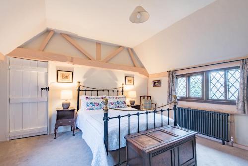 a bedroom with a bed and a table and windows at Bonnington Cottage by Bloom Stays in Canterbury
