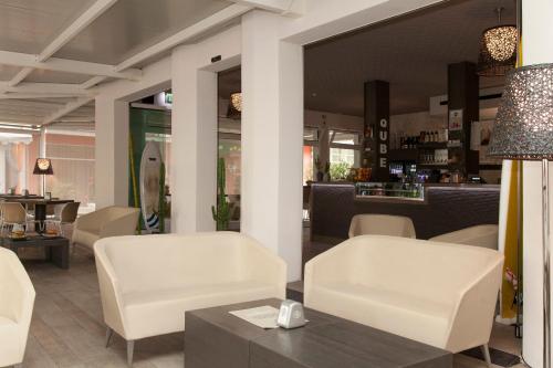 a restaurant with white chairs and a table and a counter at Hotel Helvetia in Lido di Jesolo