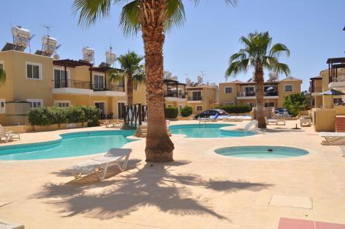 a resort with a swimming pool and palm trees at Sirena Sunrise, Apartment 4 in Paphos