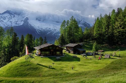 a house on a hill with mountains in the background at XL Appartements Sand in Taufers in Campo Tures