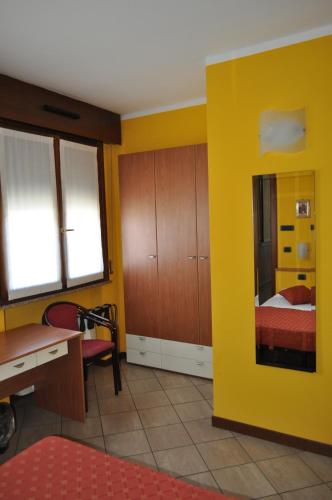 a yellow room with a desk and a bed at Hotel Mantova Sud in Bagnolo San Vito
