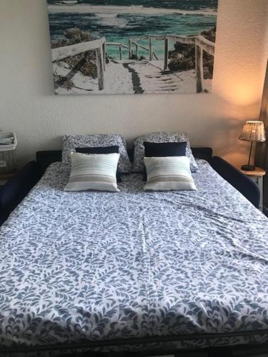 - un lit avec deux oreillers et une photo de plage dans l'établissement Perle d’horizon marin, à Sète